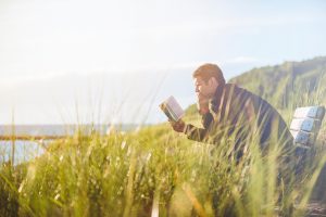 Picture of young man having daily morning revival Bible reading outdoors